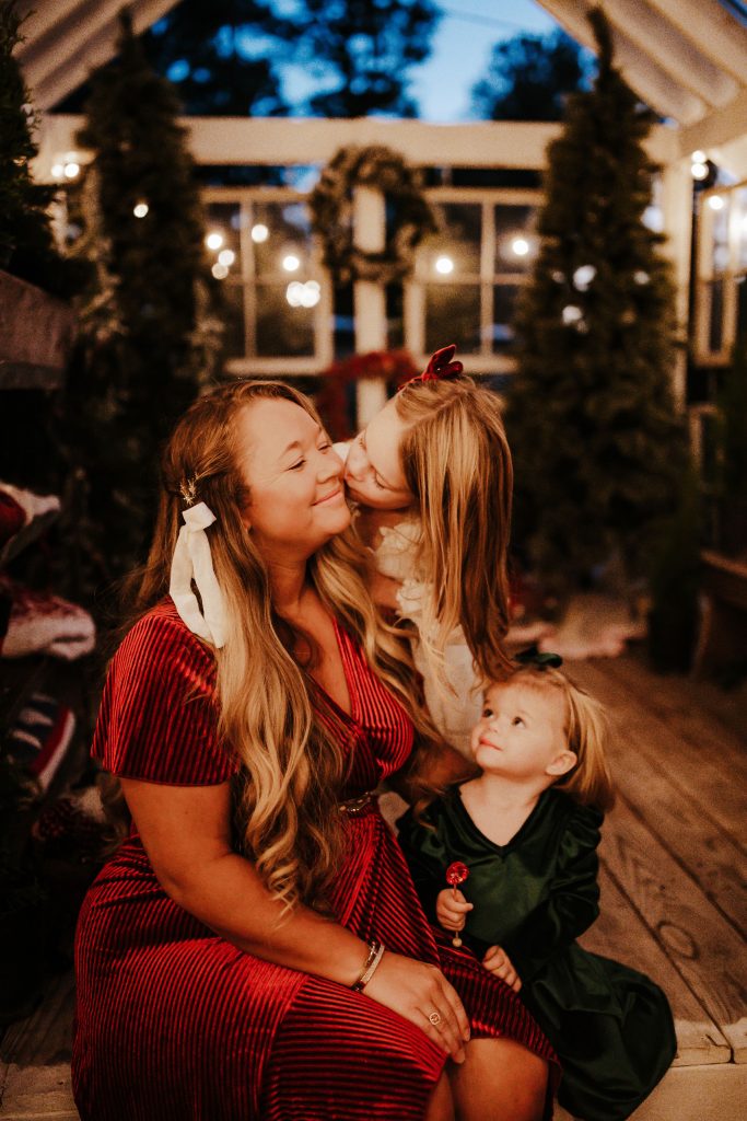 Nicki Odom and daughters kissing her cheek in Family Christmas photoshoot by Kristin Guynn