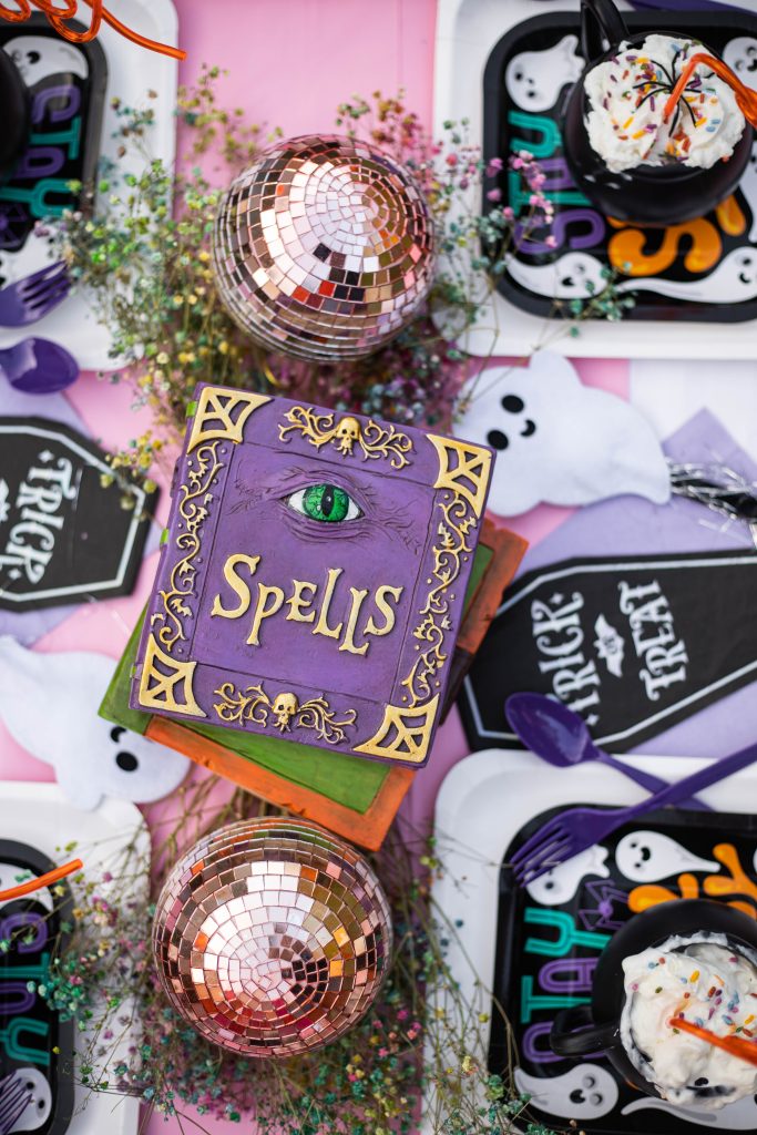 Party table setup for Halloween with spell books and halloween decorations