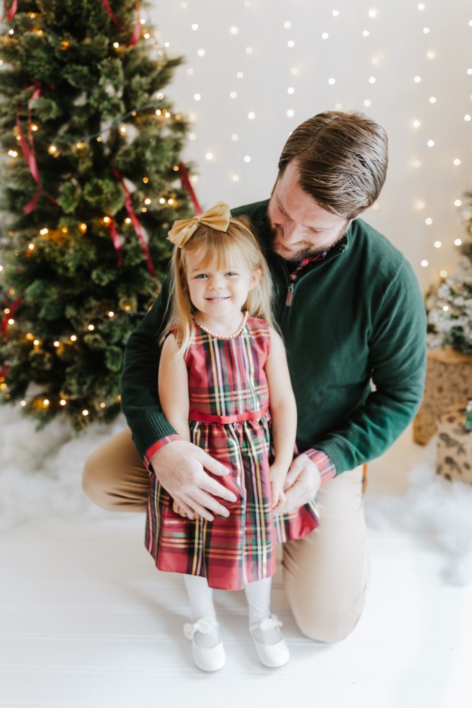 Nicki Odom's daughter and husband in family christmas photoshoot by Christmas tree