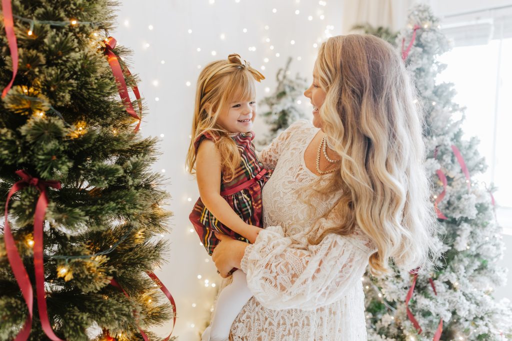 Nicki Odom with daughter beside a sparkling Christmas Tree